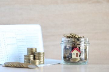 Mortgage,Model house and stack of coins money in the glass bottle on natural green background,Business investment and real estate concept