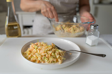 Fresh prepared coleslaw served by woman´s hands in the kitchen