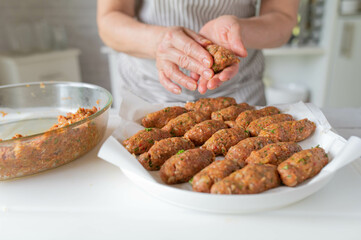 Woman preparing cevapcici in the kitchen. Delicious meat rolls for barbecue