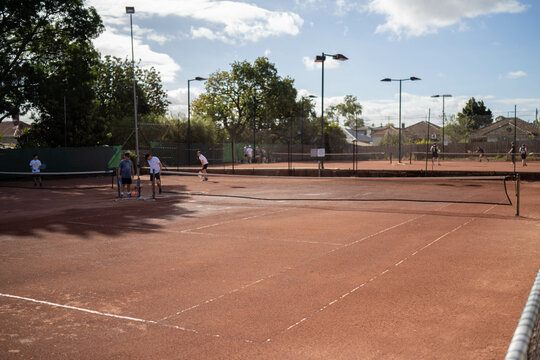 friends playing social tennis club on a clay tennis court in summer
