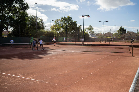 friends playing social tennis club on a clay tennis court in summer - Powered by Adobe