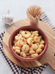 earthenware casserole with garlic shrimp, Spanish tapa on wooden board, chopsticks on the table for eating