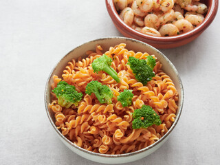 close-up view of healthy dish on the table for low carbohydrate diet. Legume pasta red lentil, broccoli florets. Garlic shrimp dish in the background.
