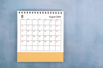Directly above view of August 2024 desk calendar on blue wooden background.