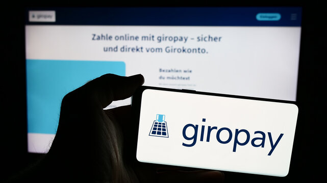 Stuttgart, Germany - 07-04-2024: Person holding smartphone with logo of German payments company Giropay (Paydirekt GmbH) in front of website. Focus on phone display.