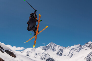Stylish skiing trick in snowy high sharp mountains. The athlete is flying
