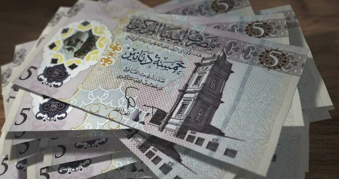 Libya dinar 5 LYD banknotes falling on the table. Libyan currency paper notes count on stack. Timelapse of money counting. 3D concept.