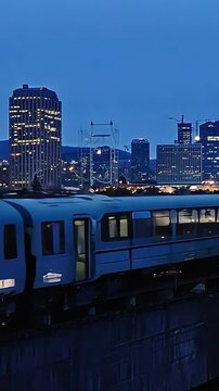 Commuter rail crosses along bridge at night with Denver city skyline in distance