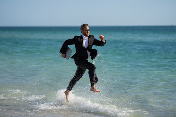 Businessman suit barefoot running on beach. Handsome business man on summer vacation. Businessman...
