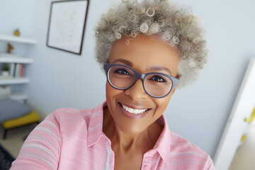 Close up photo of a happy senior African American woman in pastel shirt taking a selfie