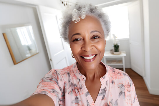 Close up photo of a happy senior African American woman in pastel shirt taking a selfie