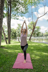 Young Healthy Woman Practicing Yoga Outdoors in a Scenic Park Setting on a Sunny Day