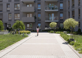 Fototapeta premium Teenage girl rides a scooter in a European yard