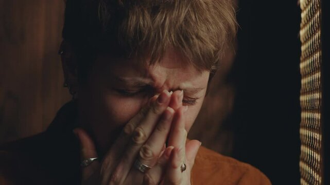 Young regretful woman crying and talking to priest emotionally during confession in church. Close-up shot
