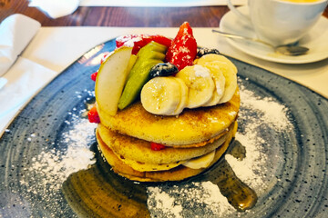 Fresh Fruit Topped Pancakes with Bananas, Apples, Berries on Ceramic Plate Perfect for Breakfast Menus and Food Blogs
