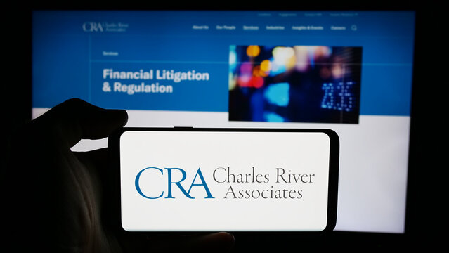Stuttgart, Germany - 07-06-2024: Person holding cellphone with logo of CRA International Inc. (Charles River Associates) in front of business webpage. Focus on phone display.