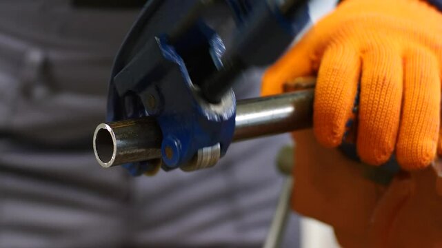plumber cuts a metal pipe with a pipe cutter