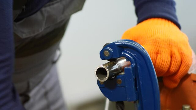 plumber cuts a metal pipe with a pipe cutter