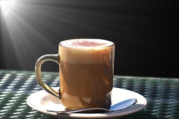 Szklanka kawy w słońcu na czarnym tle