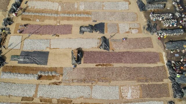 A fish market in sri lanka with fish drying on large tarps in organized rows, aerial view