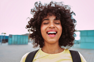 Closeup portrait of african happy smiling female student with afro hairstyle outdoors at city. School, education, college concept.