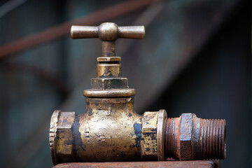 Vintage old brass water tap isolated on a dark background. tap valve. old copper retro faucet on a rusty pipe. plumbing, repair, dismantling. close-up