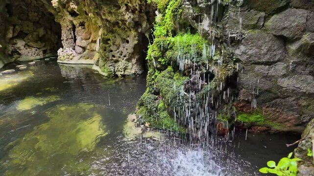 Quinta da Regaleira park in Portugal, view of the waterfall and the exit from the cave in slow motion
