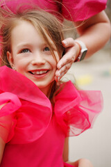 Cute happy girl in a pink dress in her mother's arms. 