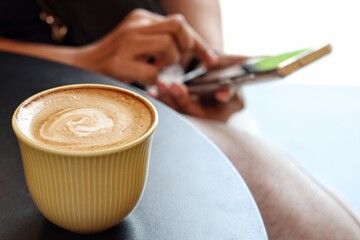 Woman using smart phone on hand and drink coffee cup