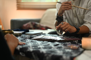 Fortune teller during a reading session talking to client at table with various spiritual items. Forecasting and divination concept