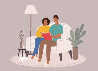 Smiling Black Couple Sitting On Couch Reading A Book Together. Full Length.