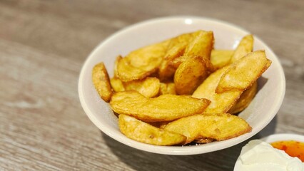 Wedge cut potato fries on wood table