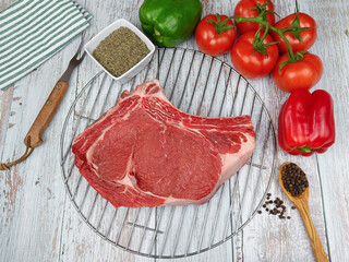 côte de boeuf cru, en gros plan, sur une grille à barbecue	