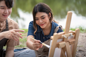 Fototapeta premium Romantic Picnic Couple Drawing Outdoors by the Lake on a Sunny Day. Artistic and Creative Moments Captured in Nature