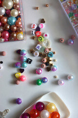 Colorful beads, letter beads, threads and other jewelry making supplies on white background. Making friendship bracelets concept. Flat lay.