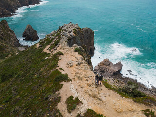 Coastal landscape in Cabo de Roca on a summer day. A couple of tourists on a cliff, photo view from a drone.