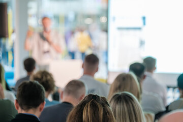 Participants attentively listening to a presenter at a business seminar or conference. The image...