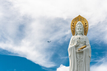 SANYA, HAINAN, CHINA Buddhist deity statue Guainin with a tourist plane in the sky