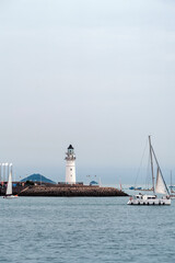 Tranquil Lighthouse and Sailboats on a Calm Sea