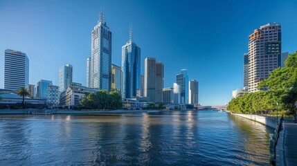 Fototapeta premium A panoramic view of city skyscrapers lining the riverbank under a clear blue sky.