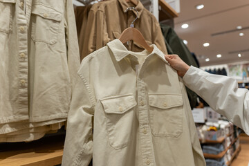 Customer Shopping for Beige Jacket in Clothing Store