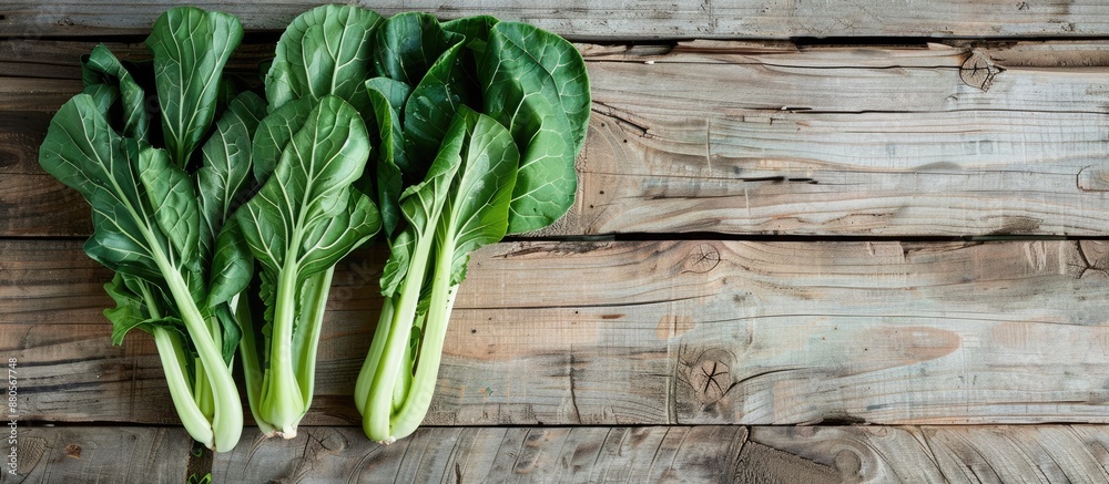 Poster Green fresh Gai lan Chinese broccoli on a wooden plank viewed from the top with a clear background suitable for text or other elements in the copy space image