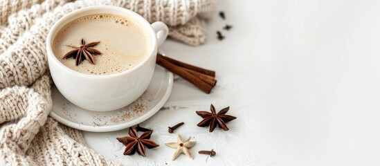 Cup of coffee adorned with cinnamon sticks and anise star set against a white background alongside a cozy sweater in a winter morning setting Ideal for a coffee break with breakfast Copy space image