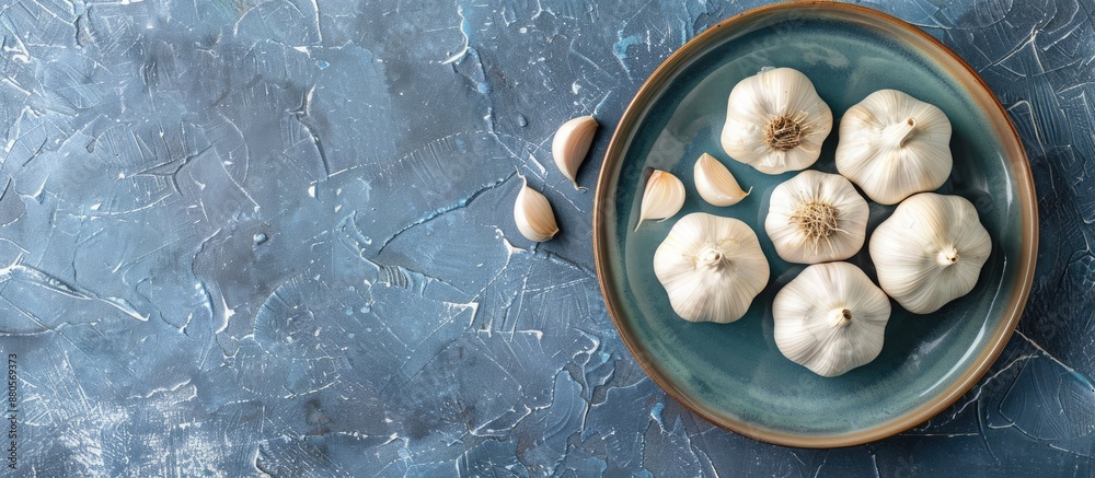 Aufkleber Copy space image of fresh garlic bulbs and cloves displayed on a plate against a blue grey stone background shot from above with selective focus and shallow depth of field