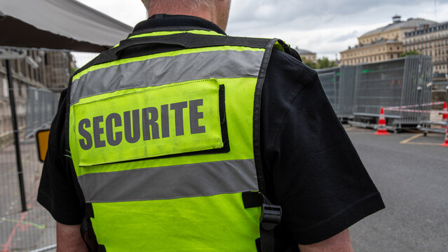 Gros plan d'un gilet jaune fluo avec le mot 's&eacute;curit&eacute;' &eacute;crit en fran&ccedil;ais port&eacute; par un agent de s&eacute;curit&eacute; priv&eacute;e surveillant un site s&eacute;curis&eacute;