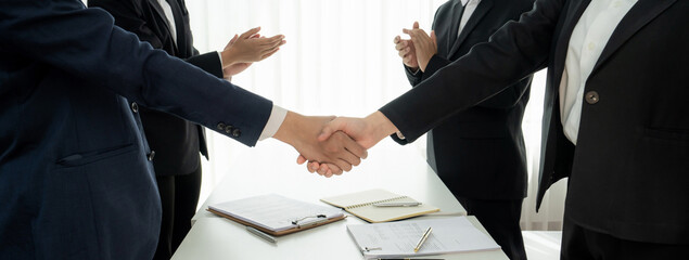 Two business executive shake hand in boardroom, sealing agreement merging two company. Handshake symbolize business partnership and cooperation. Corporate acquisition and merger concept. Shrewd