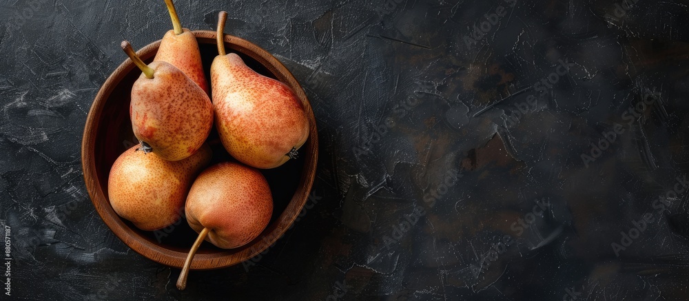 Poster A rustic style image portraying ripe brown pears in a wooden bowl against a dark background from a top view with copy space