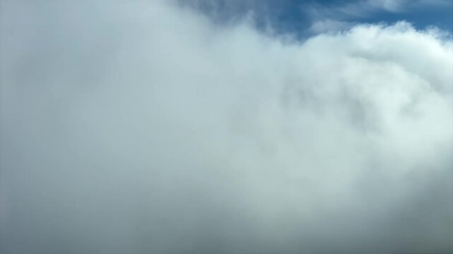 Immersive pilot POV flying through a sunny and blue sky with some white and grey cumulus clouds. Shot from an airplane cockpit. 4K 60FPS