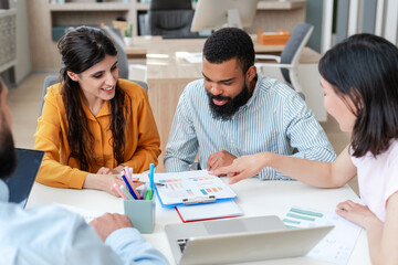 Obraz premium Diverse, multiethnic team of professionals analyzing charts and graphs during a productive meeting