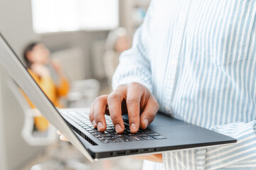 Manager standing in coworking typing on laptop selective focus, closeup